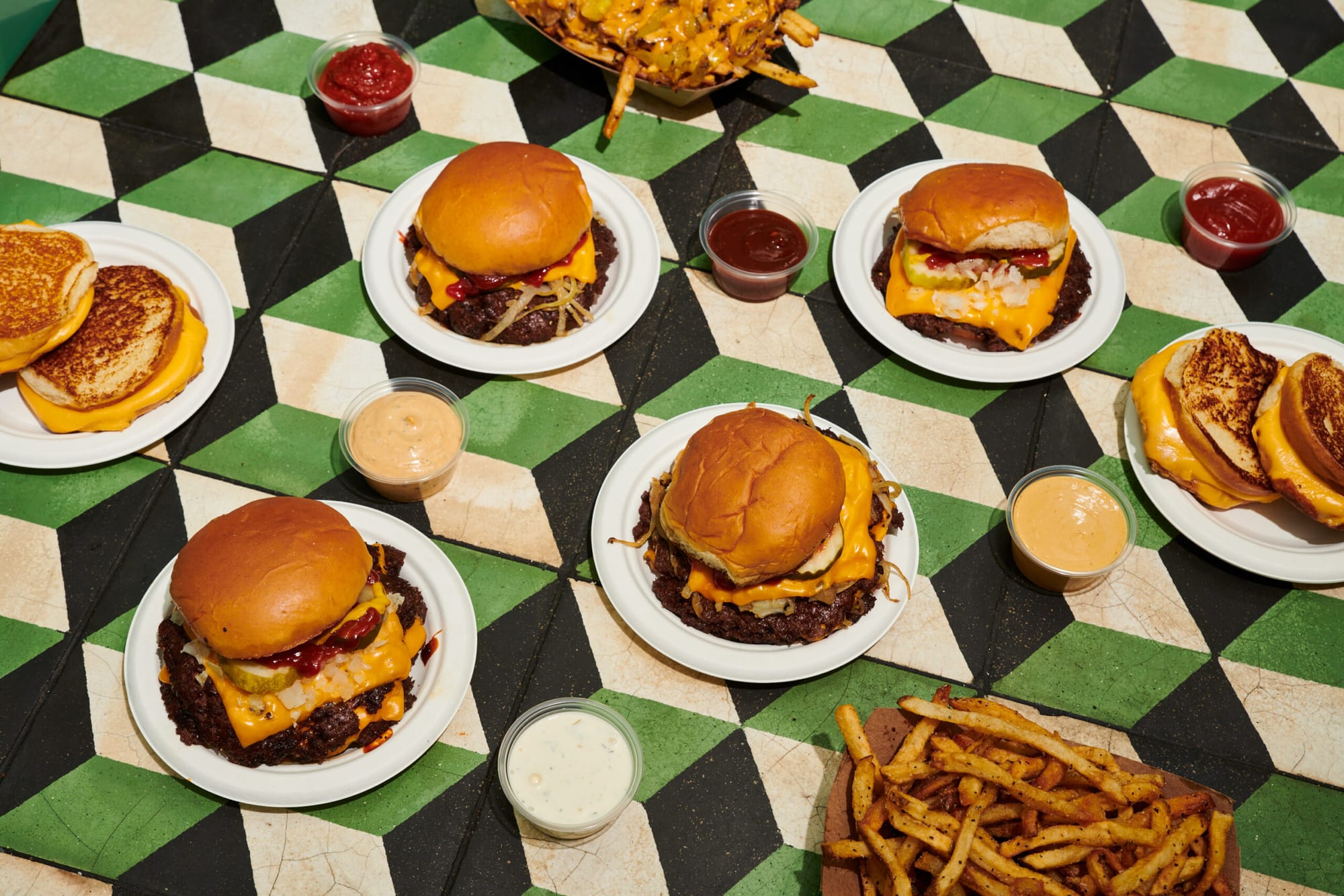 Burger She Wrote smash burgers, grilled cheese and fries laid out on the shop's green tile floor